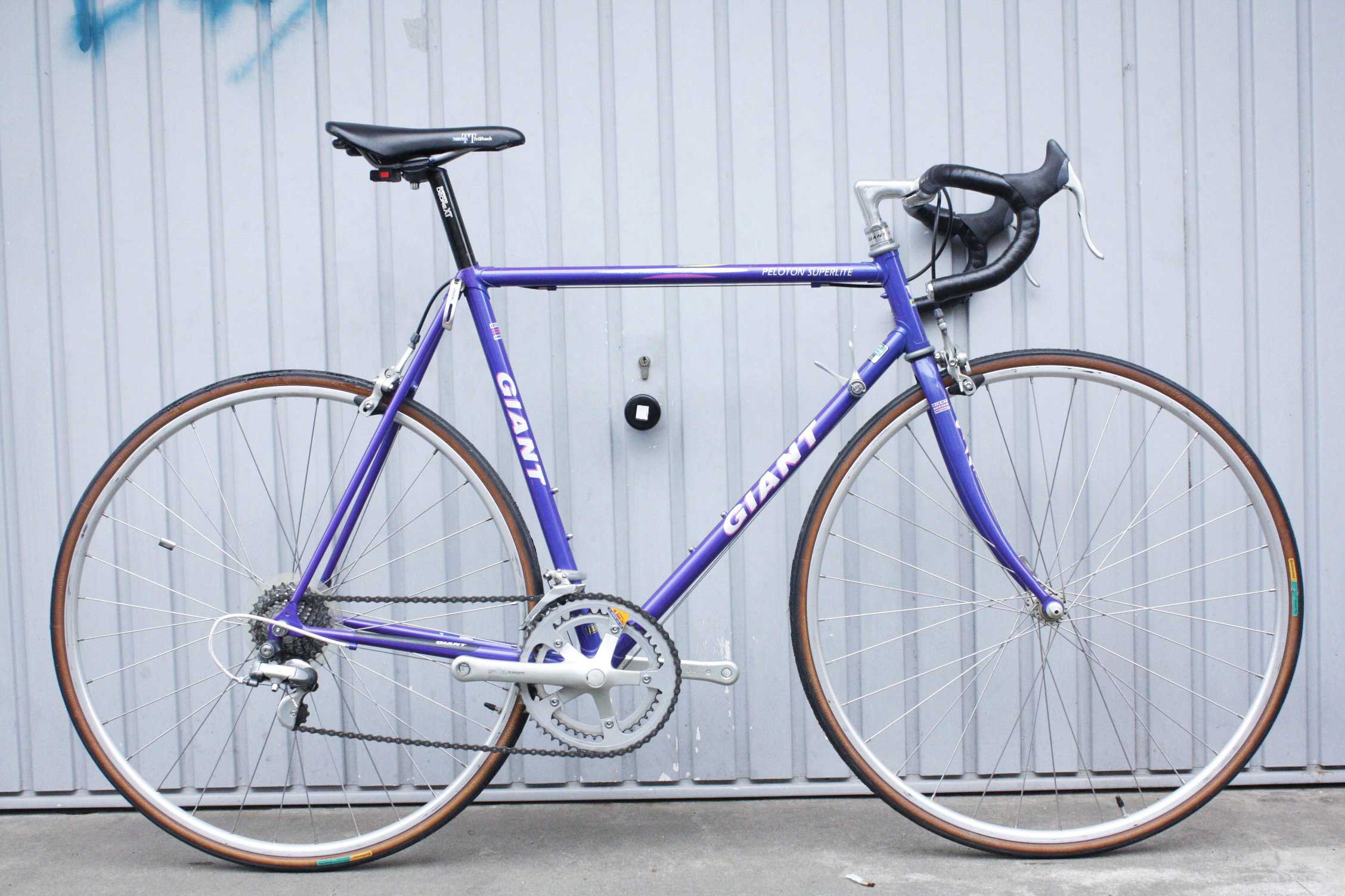 A purple framed road bike with black seat and handle bars